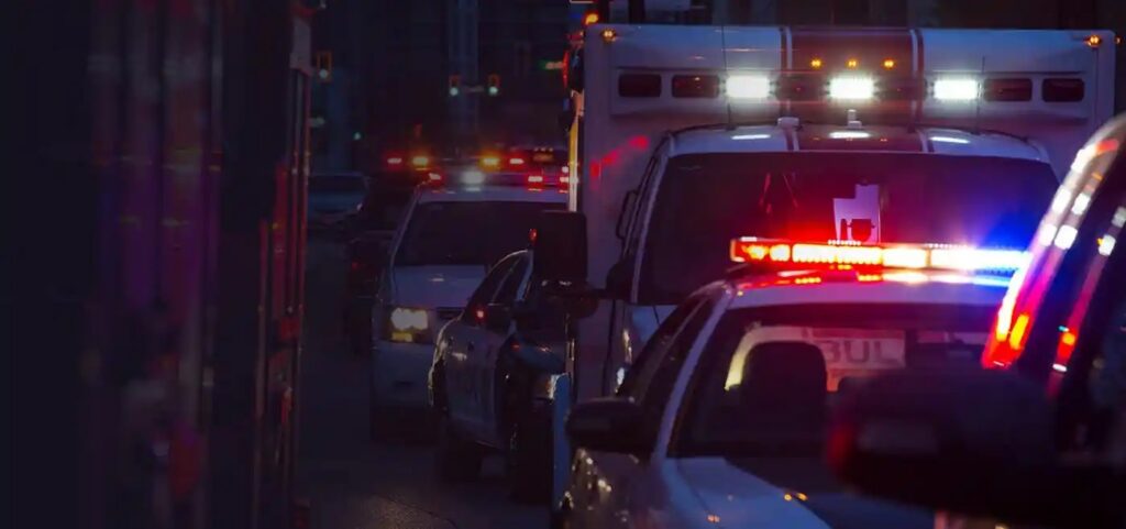 Emergency vehicles with red and blue lights on a city street at night.