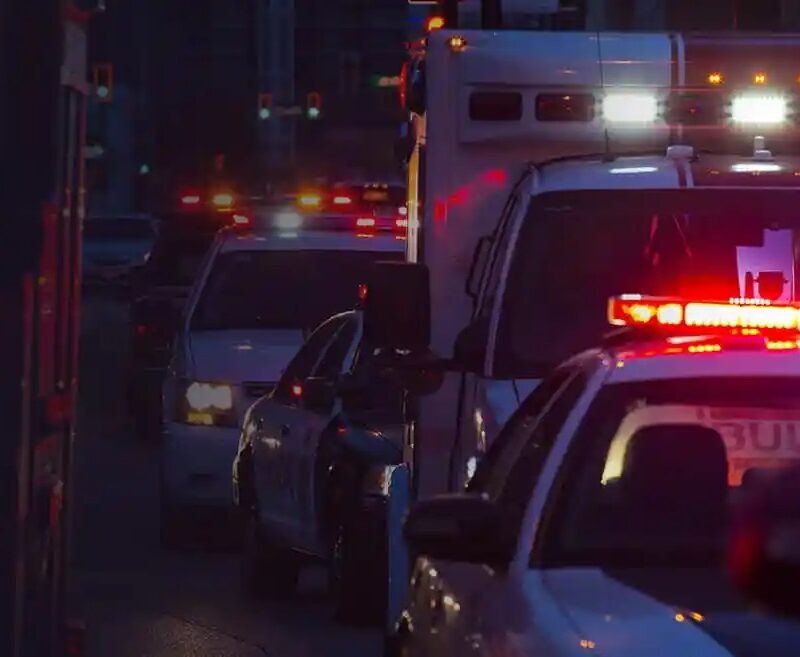 Emergency vehicles with red and blue lights on a city street at night.